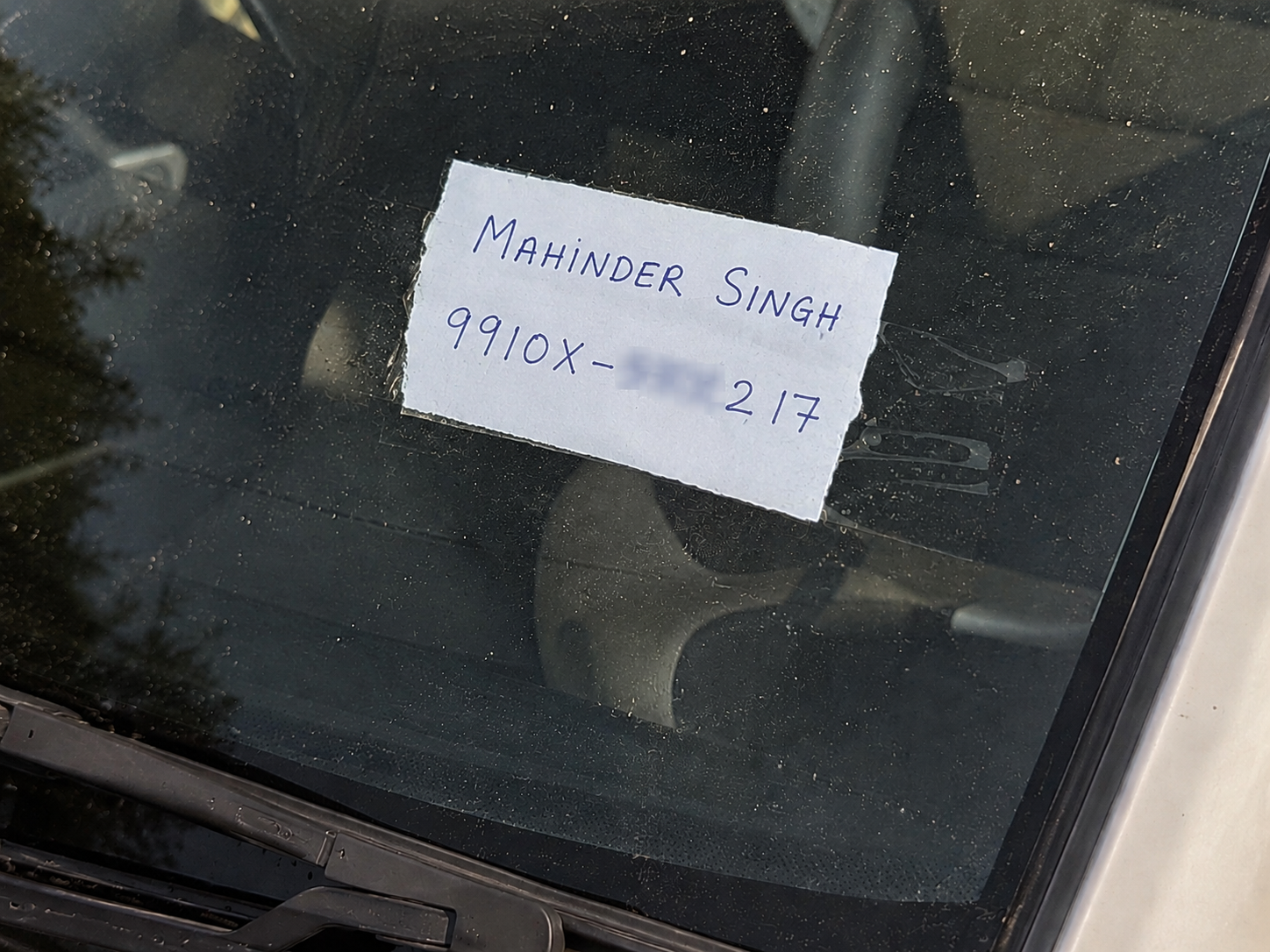 Handwritten note with phone number on car dashboard