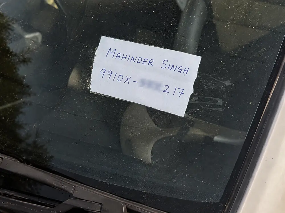 Handwritten note with phone number on car dashboard
